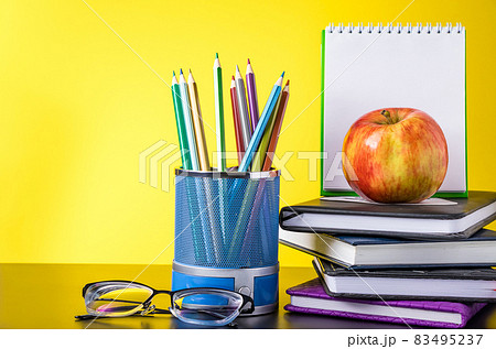 Back to school concept. School supplies, apple and books on a yellow background. Place for text. Back to school concept. School supplies, apple and books on a yellow background. Place for text. 83495237