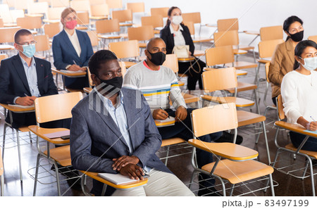 People in protective masks sitting in conference room during business training 83497199