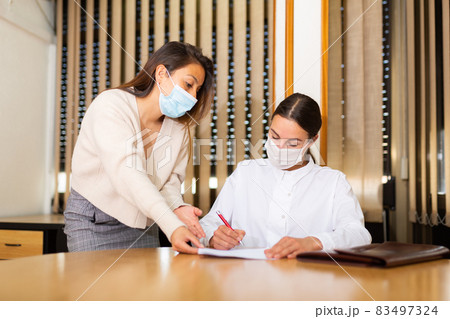 Young female in face mask signing apply for job Young female in face mask signing apply for job 83497324