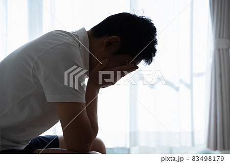 ソファに座り頭を抱える男性の様子 83498179