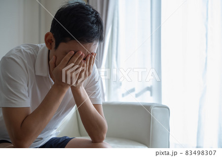 手で顔を押さえソファに座る男性の様子 手で顔を押さえソファに座る男性の様子 83498307