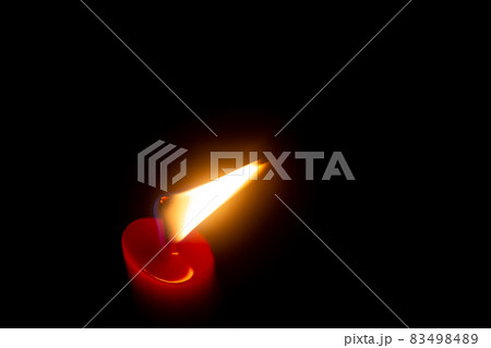 Red candle with yellow flame on black background 83498489