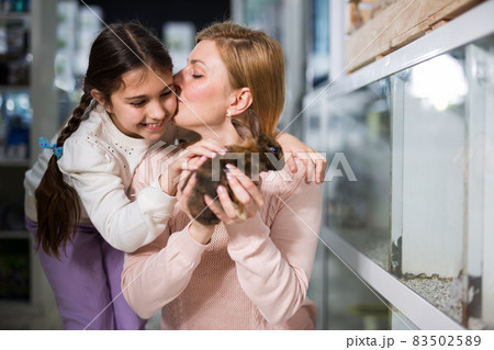 Mother with her daughter holding rabbit together at pet store 83502589
