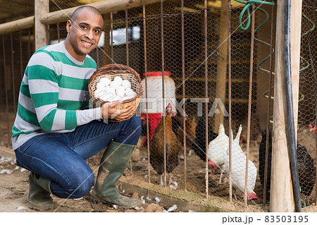 Smiling man holds a basket of chicken eggs in his hands. 83503195