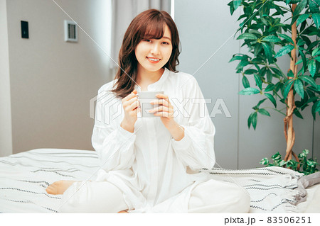 ベッドルームで飲み物を飲む女性 83506251
