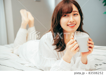 ベッドルームで飲み物を飲む女性 83506252