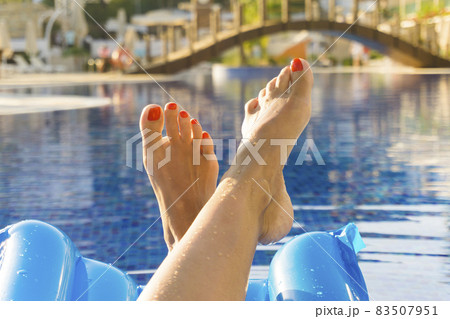Feet of a woman on the swimming pool 83507951