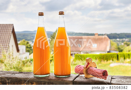 Two bottles of natural apple juice on the background of an Alsatian landscape Two bottles of natural apple juice on the background of an Alsatian landscape 83508382