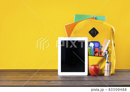 Backpack, textbooks, stationery and school supplies on wooden desk. 83509488