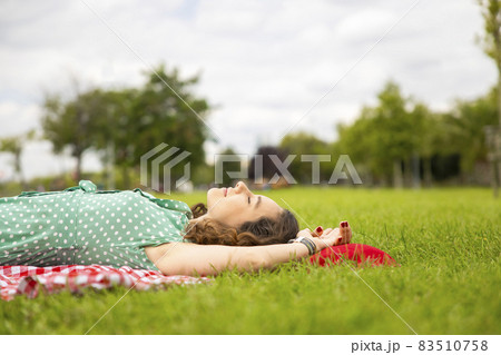 Beautiful woman resting on the grass in a parkの写真素材 [83510758] - PIXTA