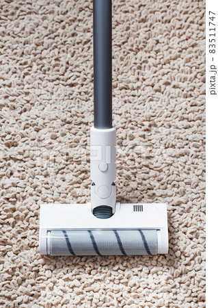 A white turbo brush of a cordless vacuum cleaner on the carpet. Indoor cleaning concept A white turbo brush of a cordless vacuum cleaner on the carpet. Indoor cleaning concept 83511747