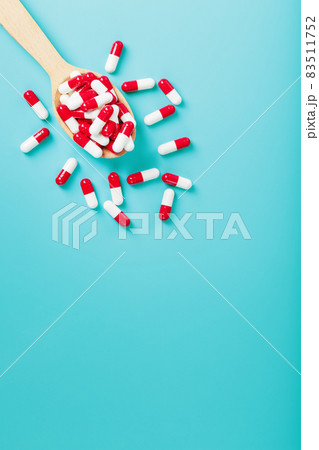 Red and white pill capsules on a blue background. Red and white pill capsules on a blue background. 83511752