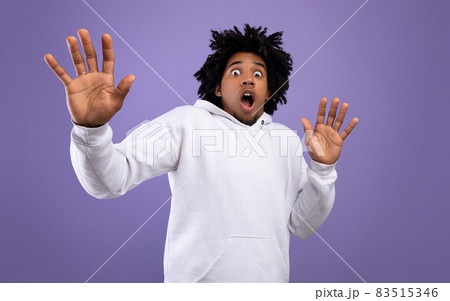 Shocked black teen guy making protection gesture, feeling frightened on violet studio background, panorama 83515346