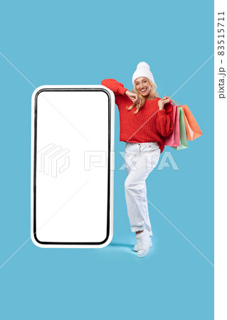 Woman leaning on white empty smartphone screen holding bags 83515711