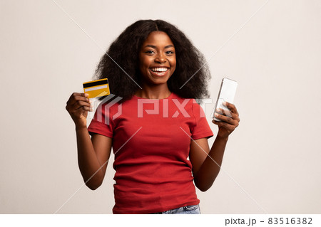 Mobile Banking. Happy Beautiful African American Woman Holding Smartphone And Credit Card 83516382