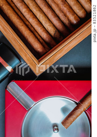 Open humidor with cigars, ashtray and cigar torch. Smoking set accessories. luxury lifestyle flat lay top view, vertical Open humidor with cigars, ashtray and cigar torch. Smoking set accessories. luxury lifestyle flat lay top view, vertical 83521862