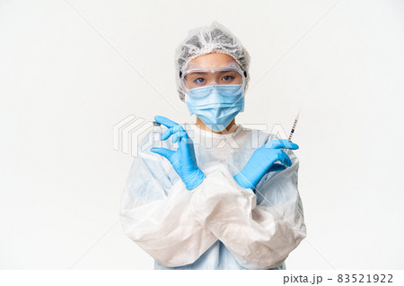 Covid-19 vaccination and health concept. Asian female doctor or nurse in personal protective equipment from coronavirus, showing vaccine covid-19 and syringe, white background 83521922