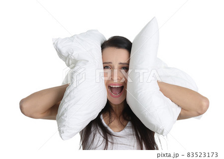 Portrait of young screaming woman covering ears with pillow Portrait of young screaming woman covering ears with pillow 83523173