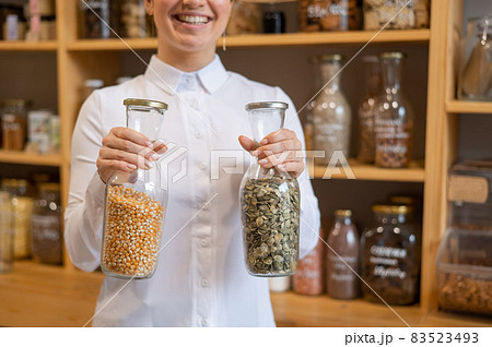 A woman holds two jars of cereals. Eco shop. A woman holds two jars of cereals. Eco shop. 83523493