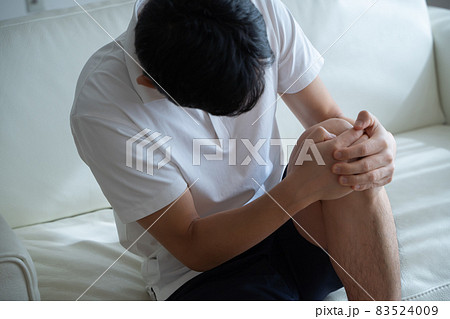 膝を抱える男性の様子 83524009