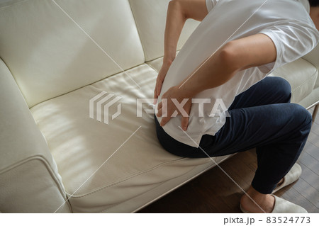 ソファに座り腰に手をあてる男性の様子 83524773