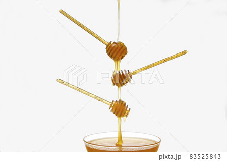 Fresh flower honey drips from a spoon into a spoon on a white background. Organic vitamin food. 83525843