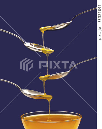 Fresh floral honey drips from a spoon into a spoon on a blue background. Organic vitamin food. Fresh floral honey drips from a spoon into a spoon on a blue background. Organic vitamin food. 83525845