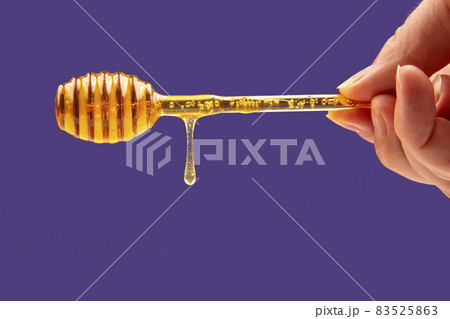 fresh fragrant honey drips from a spoon in hand on a blue background. organic vitamin nutrition 83525863
