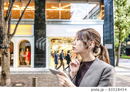 東京丸の内でスマホを操作する真剣な表情の若い女性 83528454