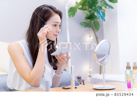 鏡を見てファンデーションを塗る女性 鏡を見てファンデーションを塗る女性 83529434