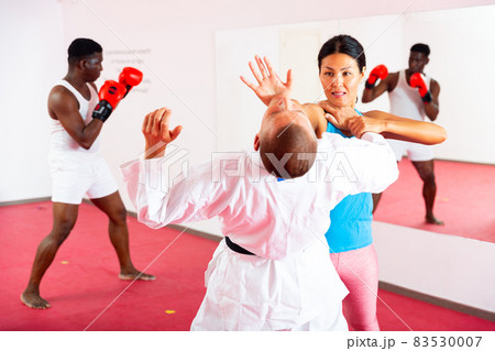 Active woman with professional trainer are training captures on self-defense course 83530007