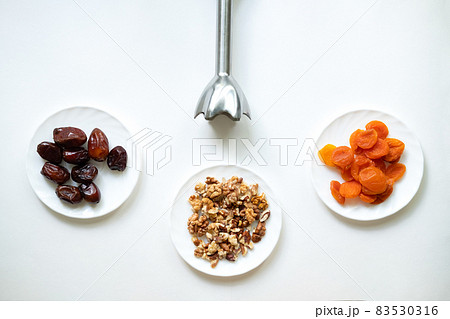 dates, dried apricots, walnuts, blender on a white background. Useful candies without sugar. dates, dried apricots, walnuts, blender on a white background. Useful candies without sugar. 83530316