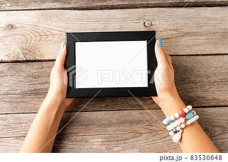 Woman hand holding empty photo frame on wooden table. Top view 83530648