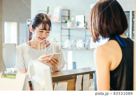 受付でスマホを出す女性 83531089