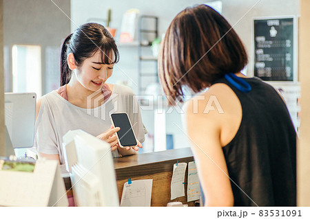 受付でスマホを出す女性 83531091