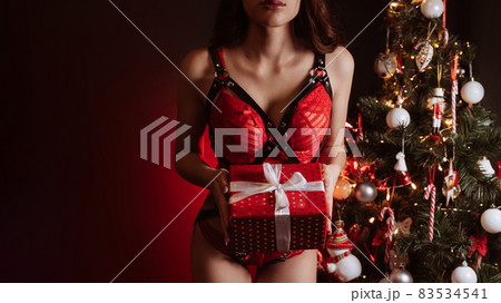 sexy body of a girl with a gift box in her hands at the Christmas tree at the new year sexy body of a girl with a gift box in her hands at the Christmas tree at the new year 83534541
