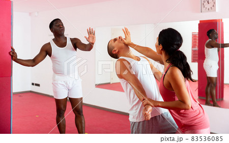 Woman is trained in self defense in pair with the help of trainer in gym 83536085