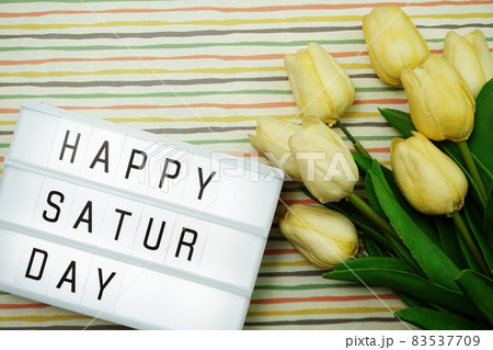 Top view Happy Saturday Text in Light box flat lay with tulip flower bouquet Top view Happy Saturday Text in Light box flat lay with tulip flower bouquet 83537709