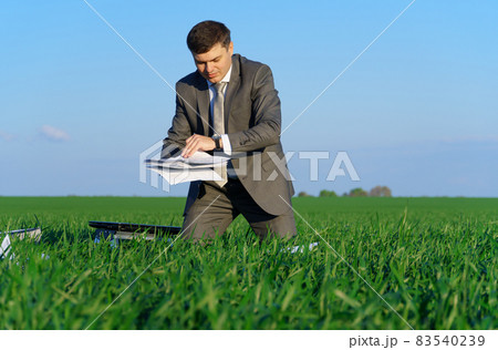 businessman works in a green field, freelance and business concept, green grass and blue sky as background 83540239