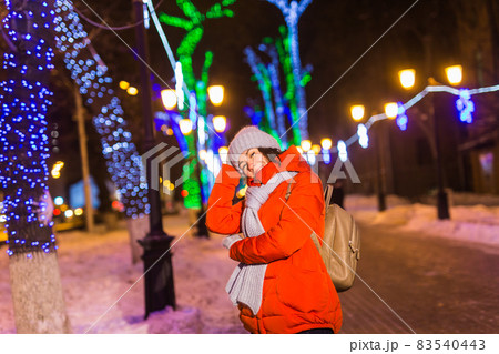 Winter holiday season. Christmas, New Year concept. Funny happy woman spend time having fun near illuminated and decorated showcase on city street. 83540443