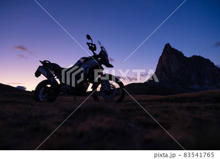 The silhouette of a motorcycle against the backdrop of mountains and sunset. 83541765