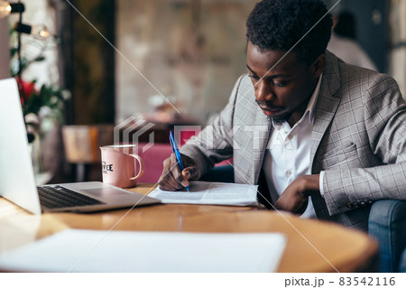 Black man working with documents, writing on paper Black man working with documents, writing on paper 83542116
