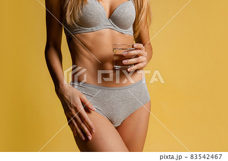 Beautiful body of young slim woman in gray underwear isolated on yellow studio background. Natural beauty concept. Beautiful body of young slim woman in gray underwear isolated on yellow studio background. Natural beauty concept. 83542467