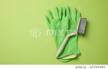 green rubber gloves for cleaning, brushes on a green background 83544460