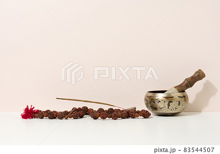 copper singing bowl and wooden clapper on a white table. Musical instrument for meditation, relaxation, various medical practices related to biorhythms, normalization of mental health 83544507