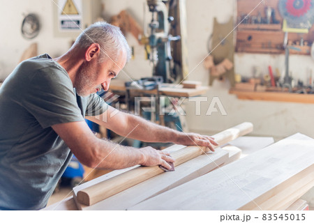 Standing senior man sanding wood with his arms Standing senior man sanding wood with his arms 83545015