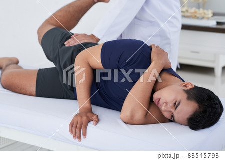 Horizontal shot of young Asian man getting physical rehabilitation manipulations at professional physical therapists 83545793