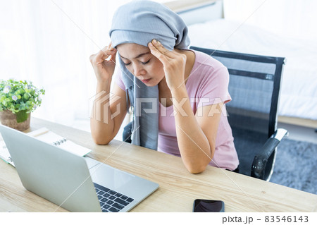 a asian women disease mammary cancer patient with pink ribbon Have a headaches wearing headscarf After treatment to chemotherapy with working business at laptop in office at home,medicine concept 83546143