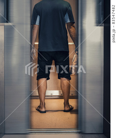 Rearview of an asian deliveryman with the elevator doors closing 83547482