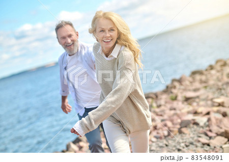 Energetic pretty woman and man running near sea Energetic pretty woman and man running near sea 83548091